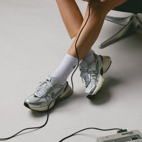 کفش زنانه اسپرت نقره ای رنگ نایک مدل V2K و زیره ی کرم رنگ داخل پا کنار کنسول بازی